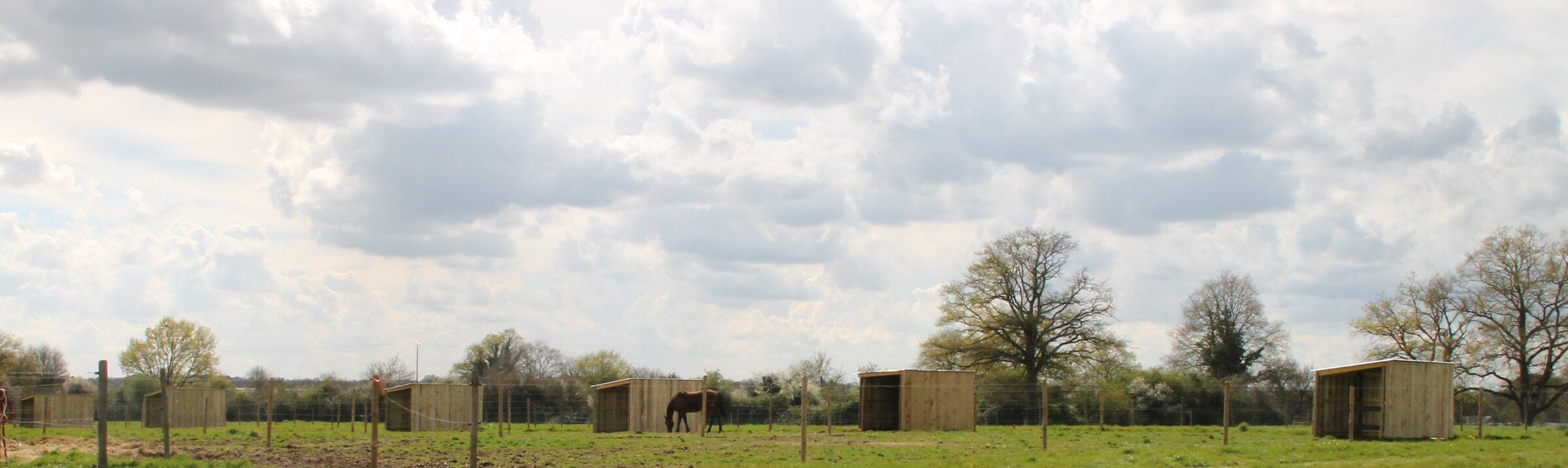 Fenced fields and a row of wooden shelters