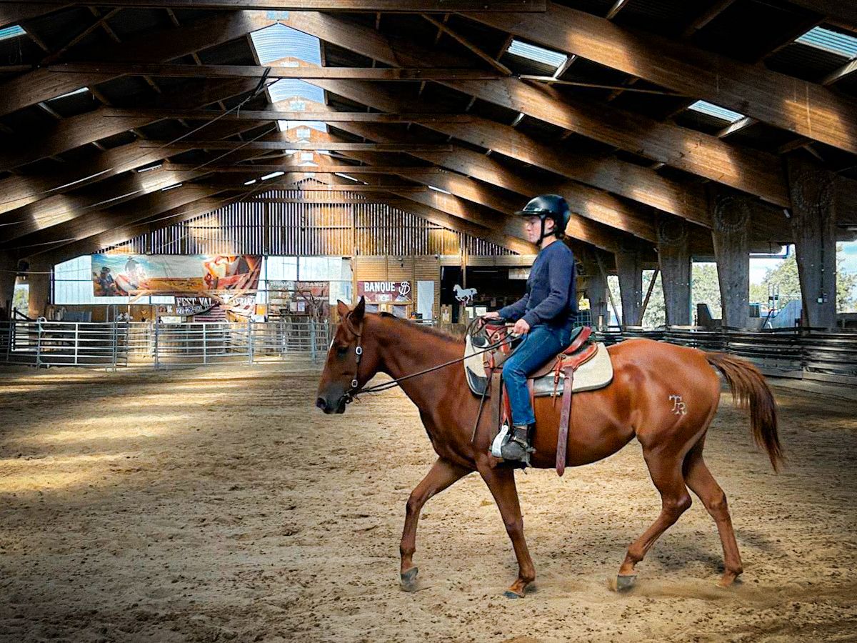 Rider trotting on a sorrel horse in the ranch’s indoor arena