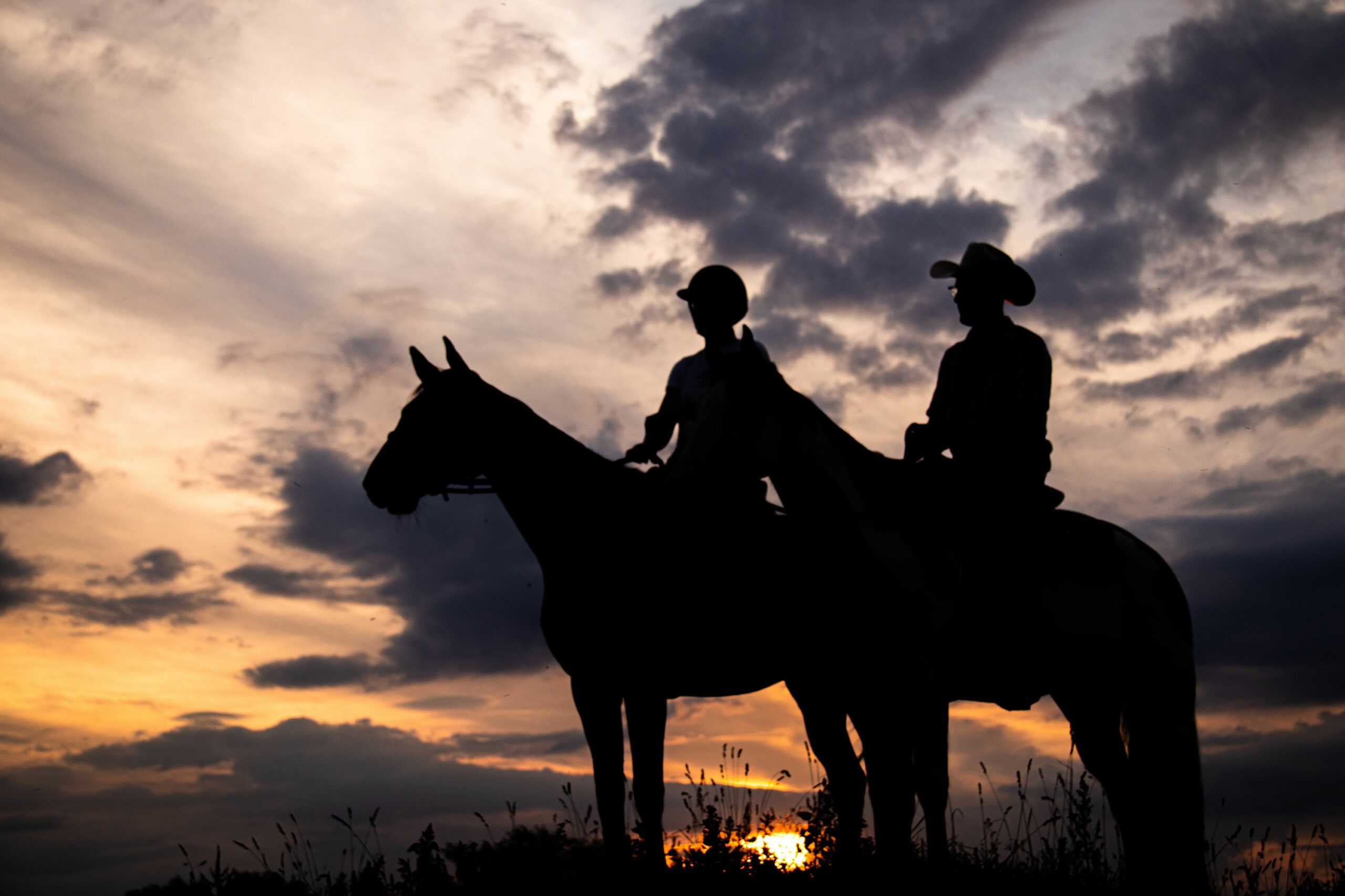 Deux cavaliers en silhouette au coucher du soleil