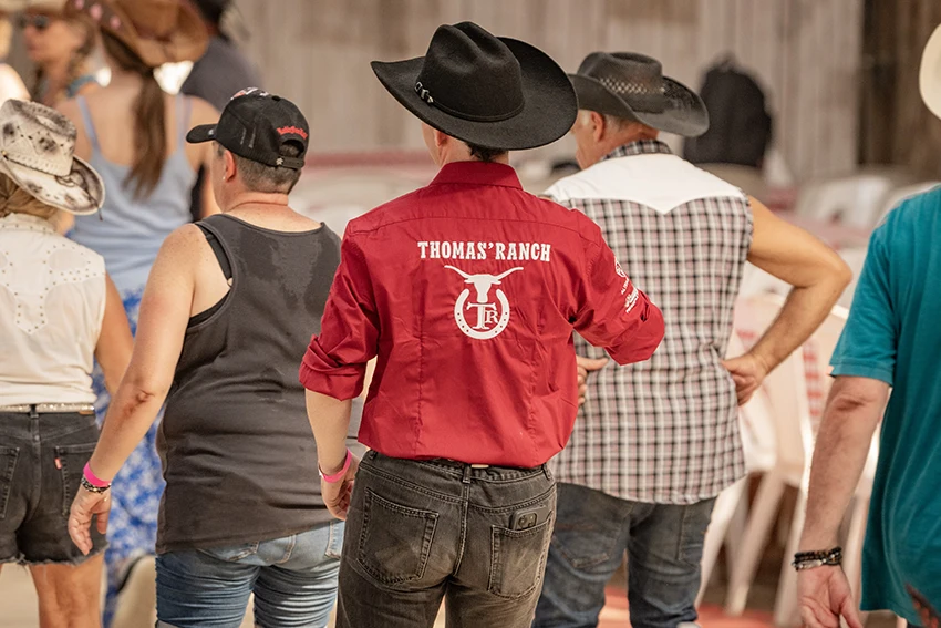 Danseur de dos en chemise rouge brodée Thomas’ Ranch pendant le bal country du festival