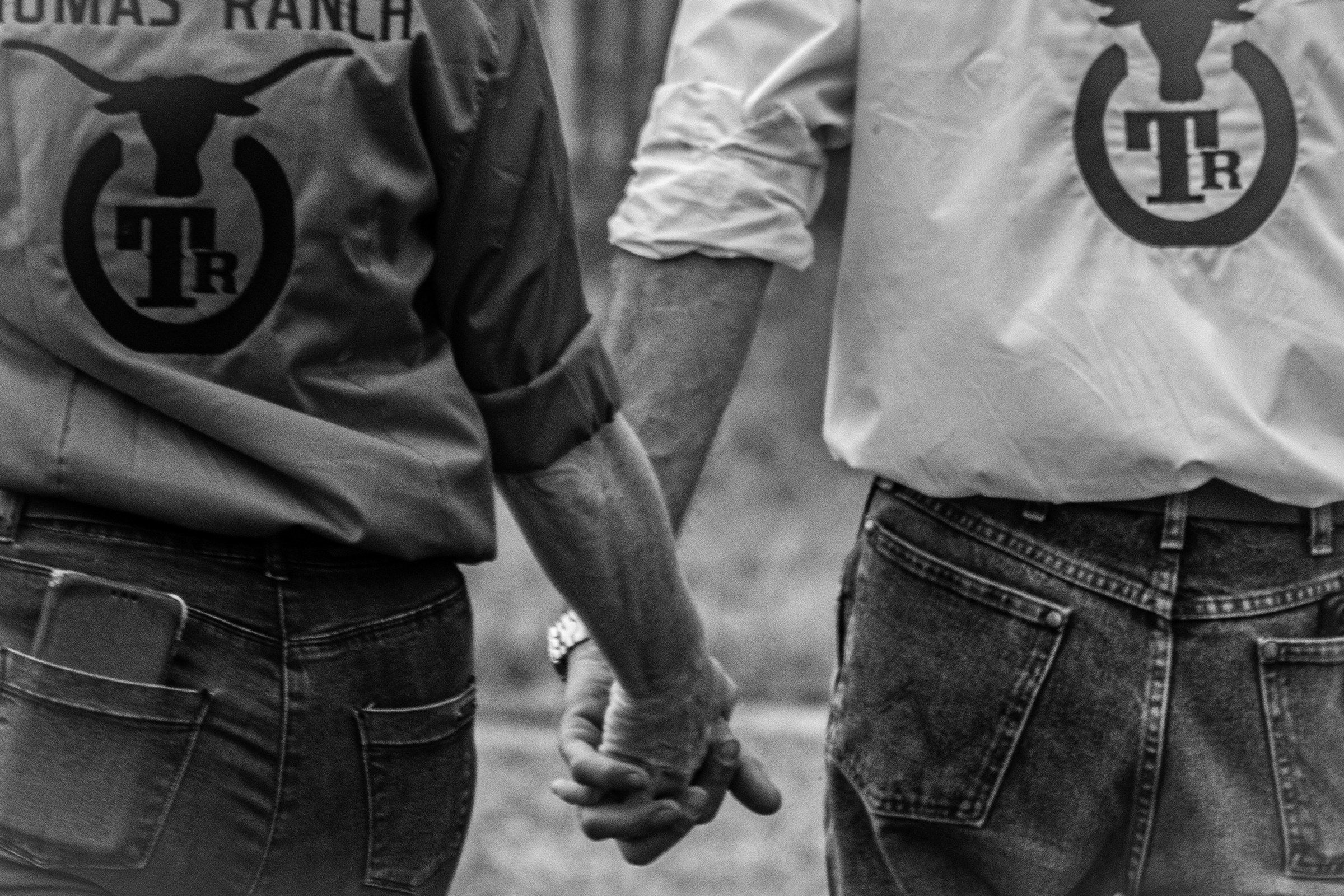 Deux bénévoles main dans la main, de dos, chemises brodées du logo du ranch, en noir et blanc