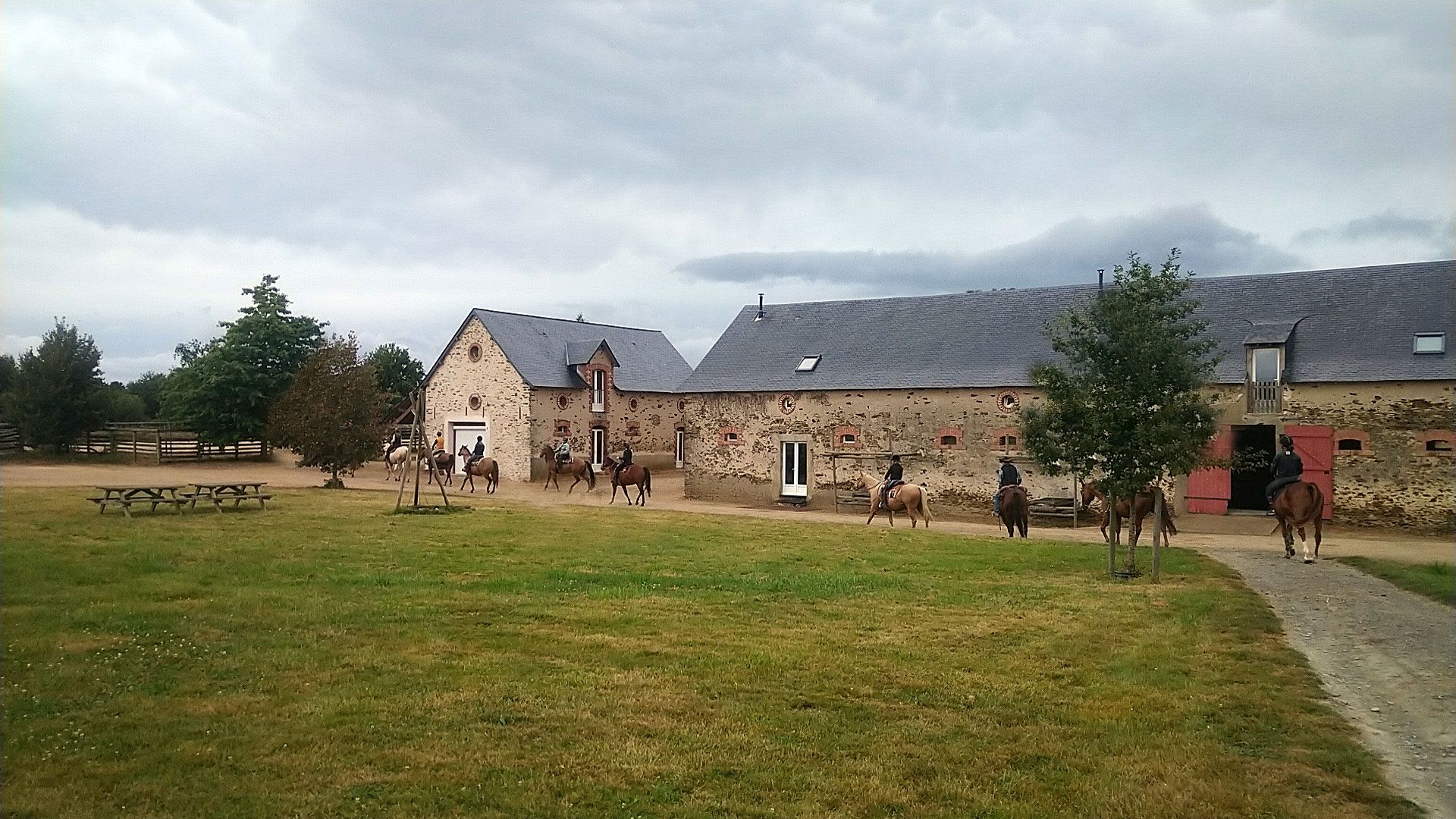 The ranch’s stone farm buildings, with riders on the lawn