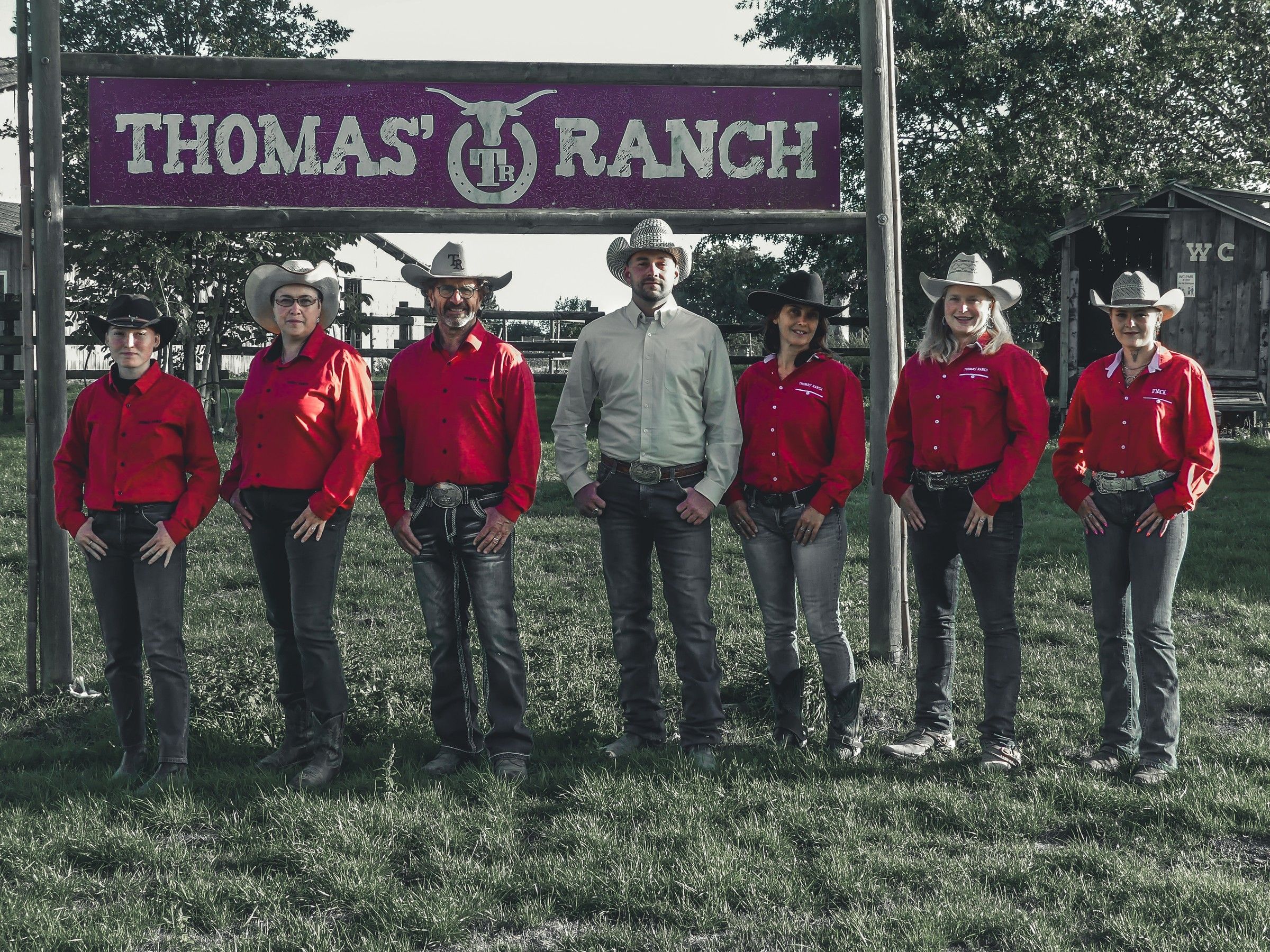 L’équipe du ranch en chemises rouges et chapeaux, devant le portique Thomas’ Ranch