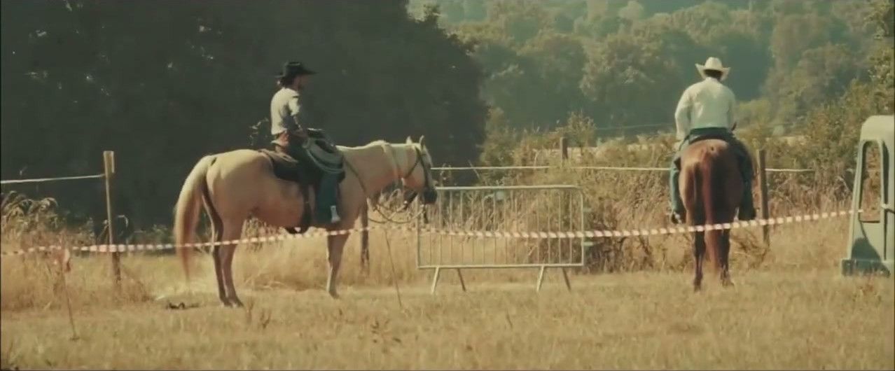Deux cavaliers western au pas dans un pré du ranch pendant le festival