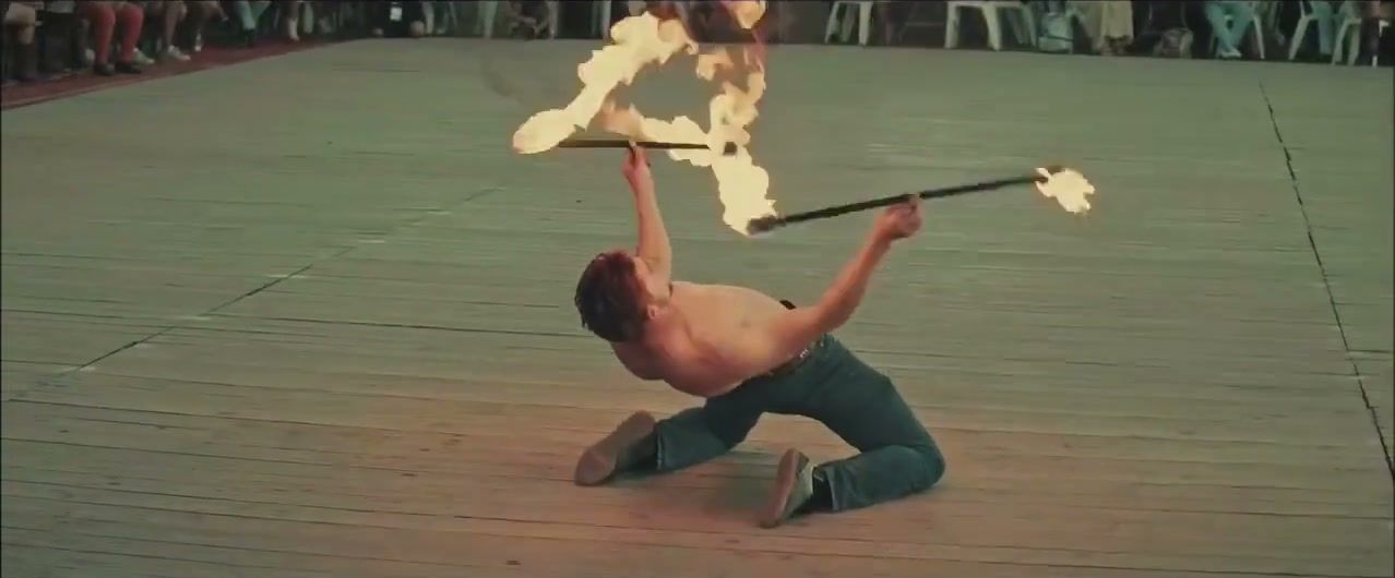Artiste de feu à genoux sur le parquet, deux torches enflammées à la main