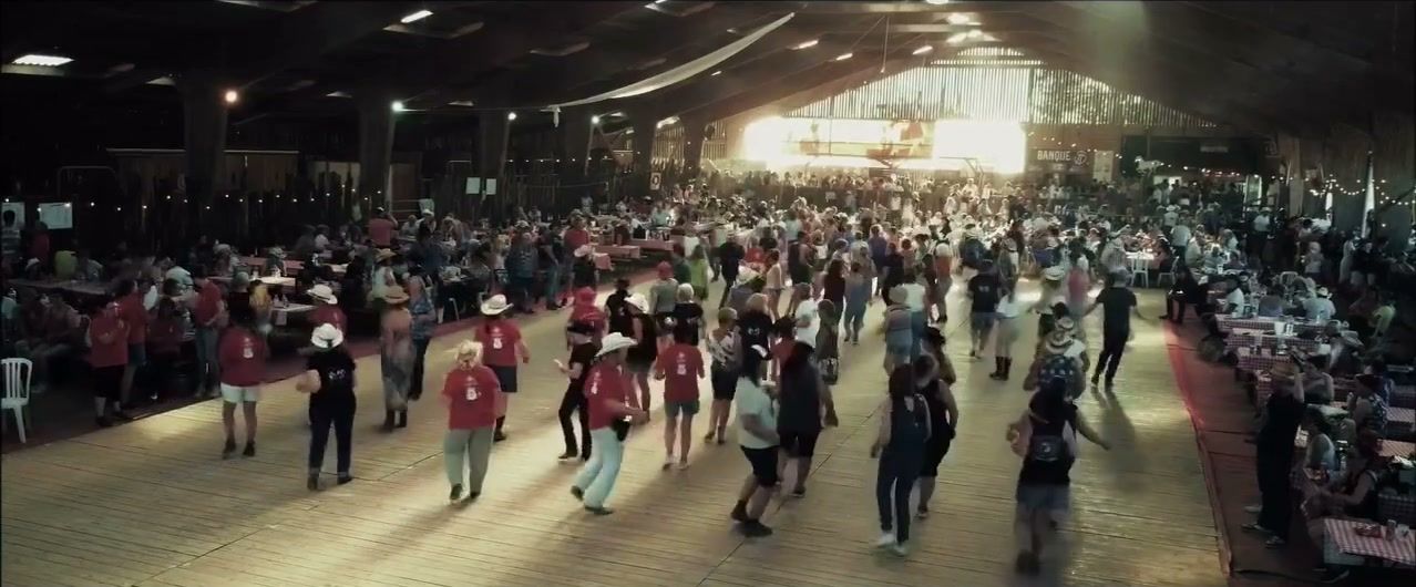 Danseurs de country sur le parquet du manège, lumière du soir à l’entrée
