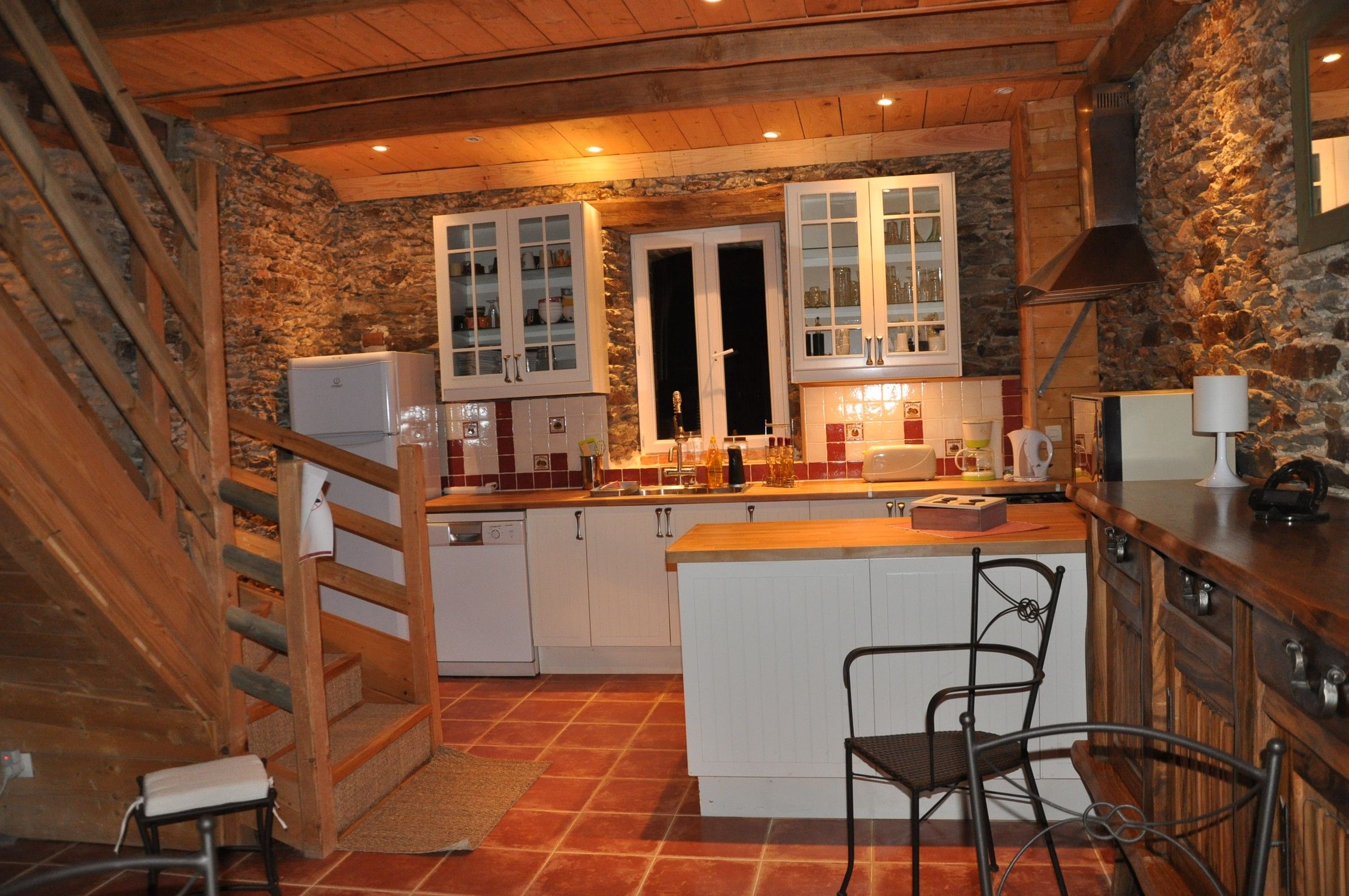 La cuisine du Little Ranch, murs en pierre, tomettes et escalier en bois