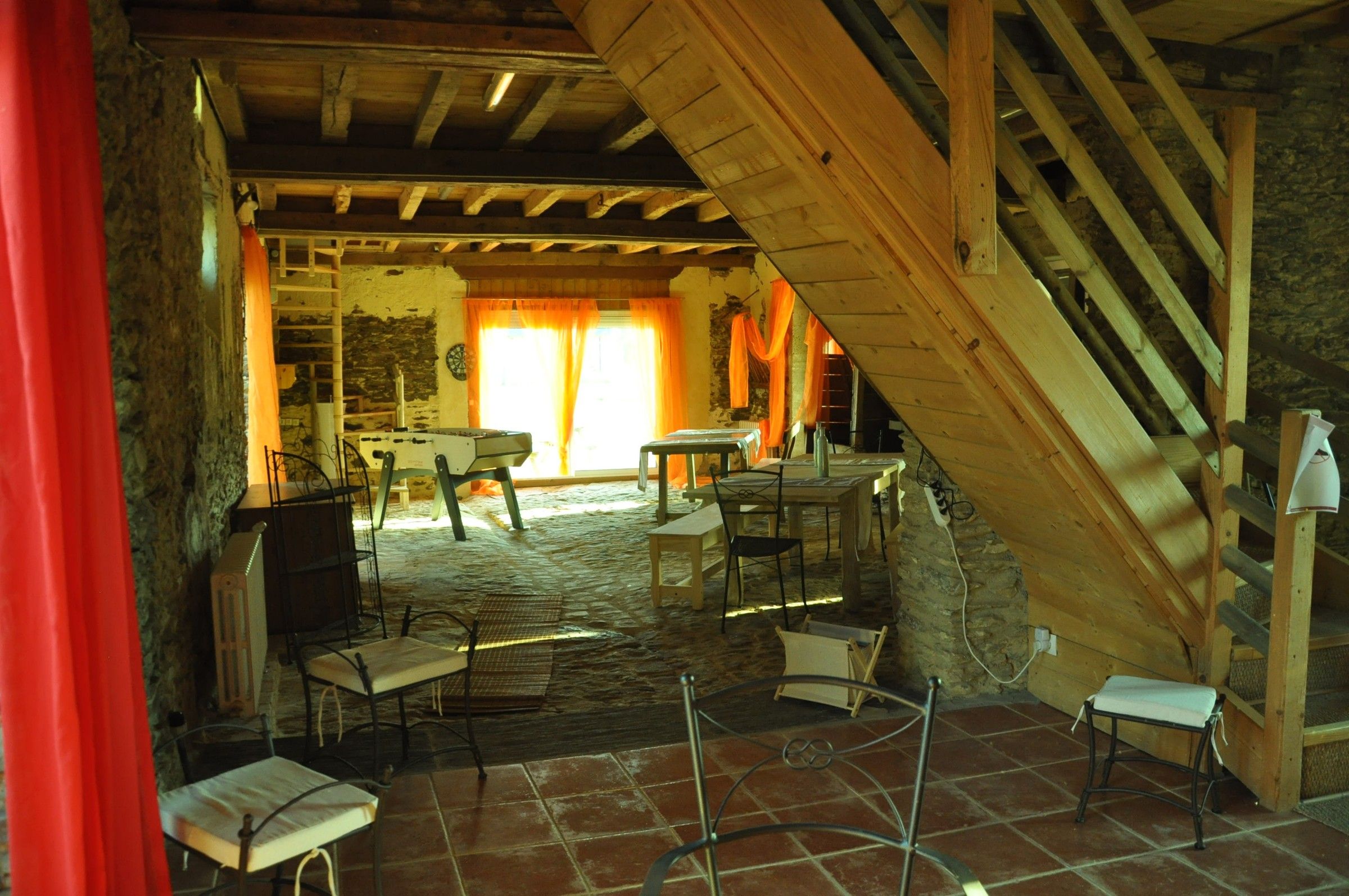 La pièce de vie du Little Ranch, escalier en bois et rideaux orange