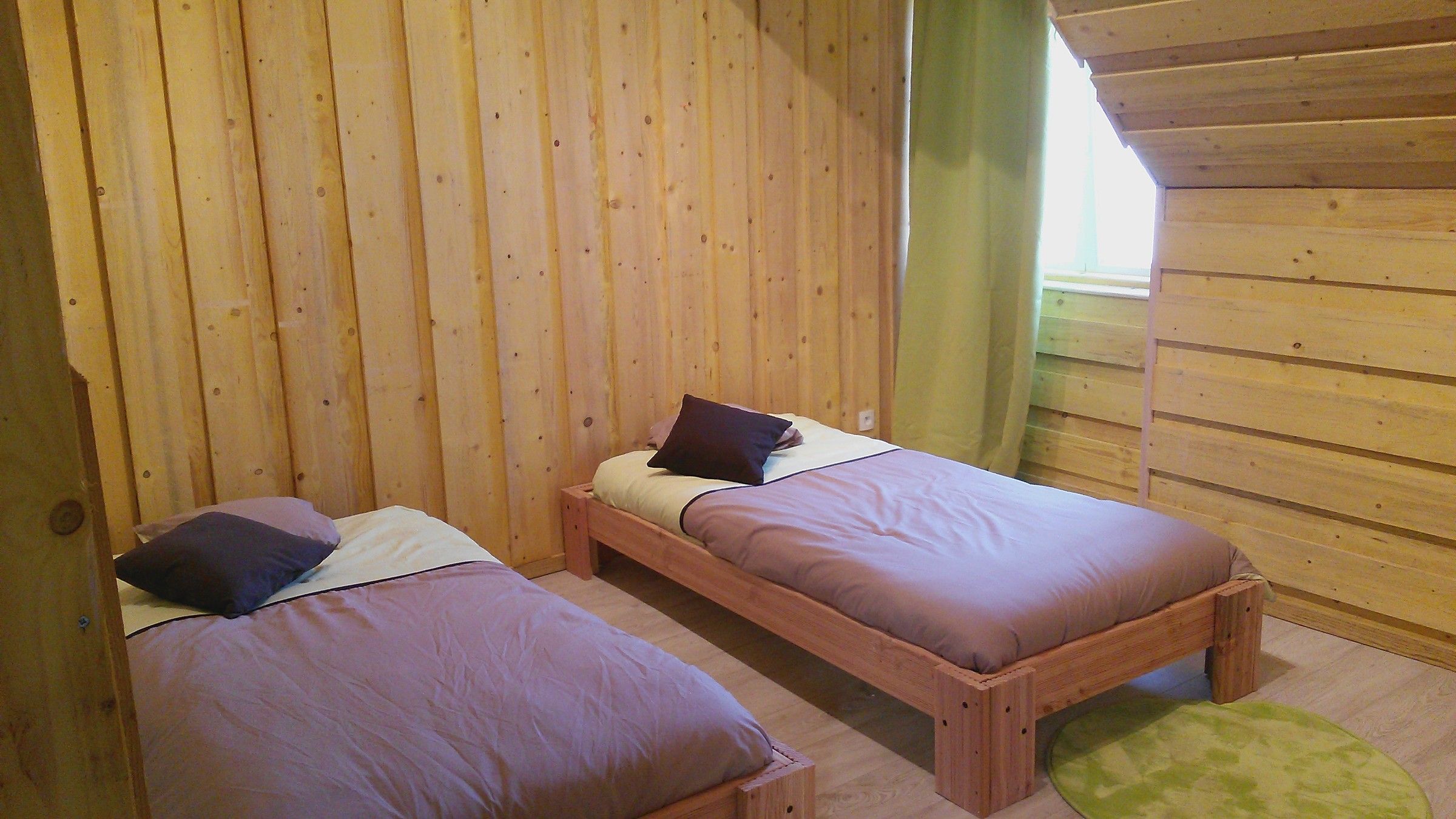 Une chambre du Loft avec deux lits en 90 cm, murs en bois clair