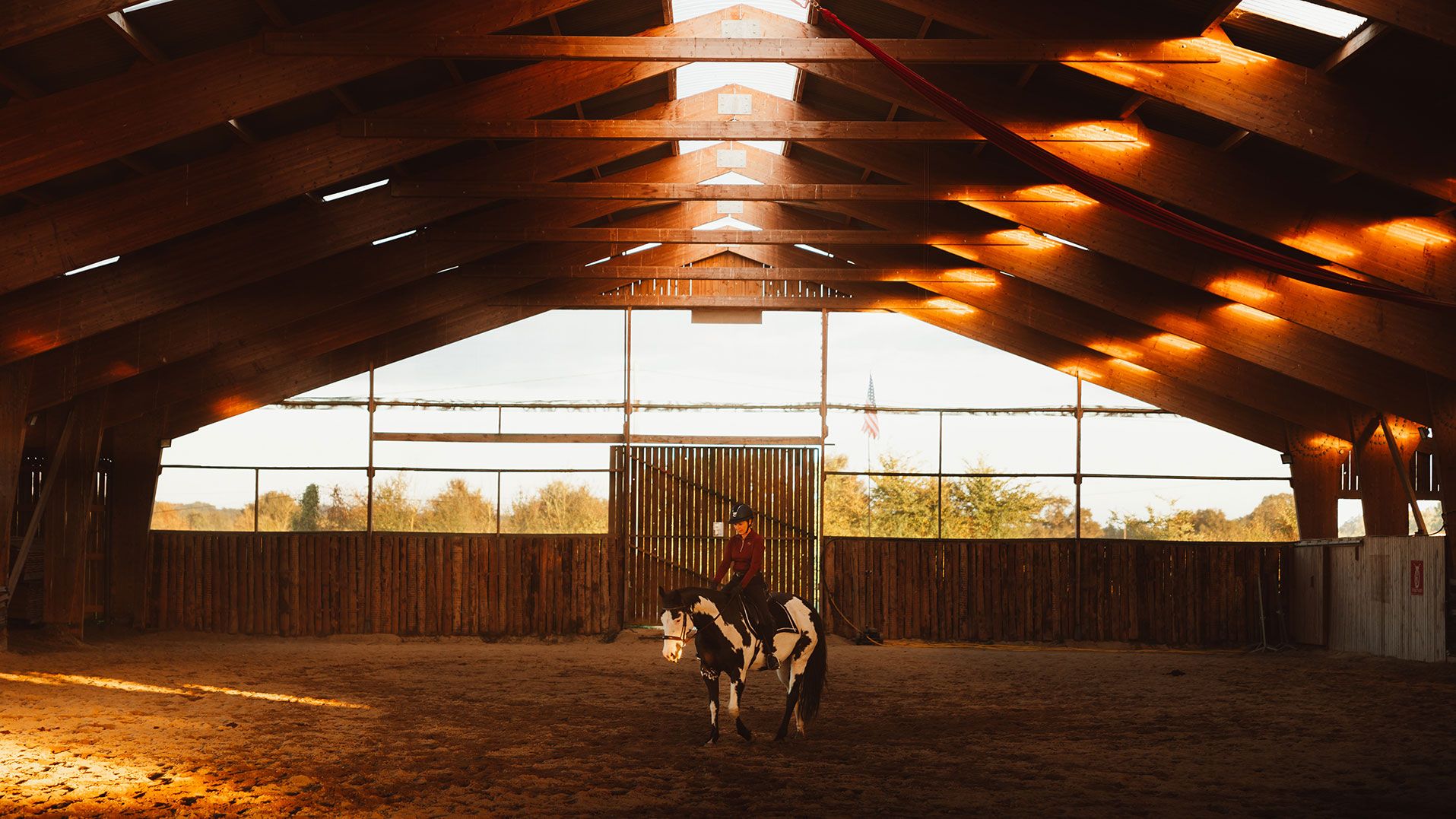 The ranch’s indoor arena at sunset, under its timber roof frame