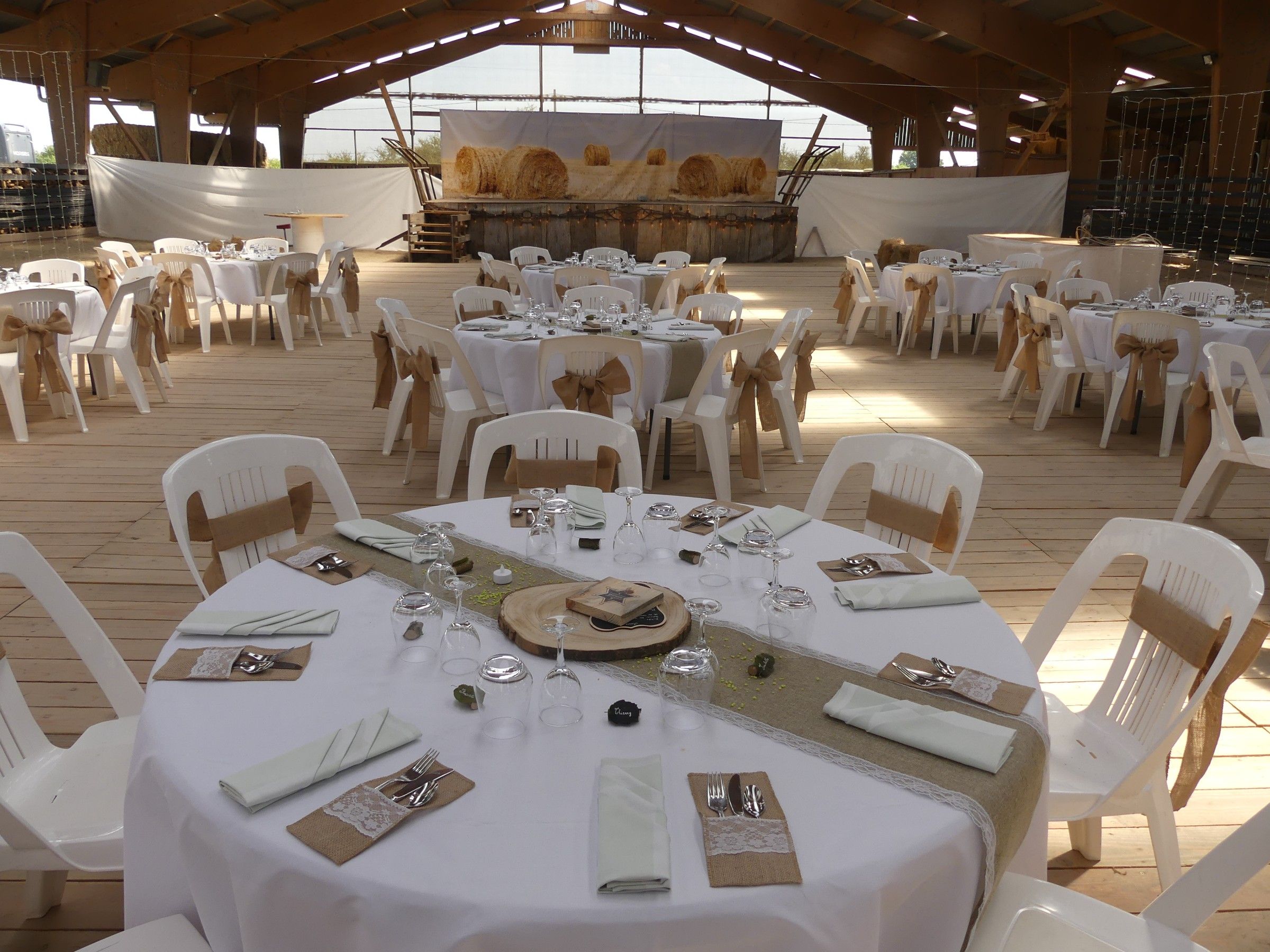 Tables rondes nappées de blanc et chaises nouées de toile de jute dans le manège du ranch