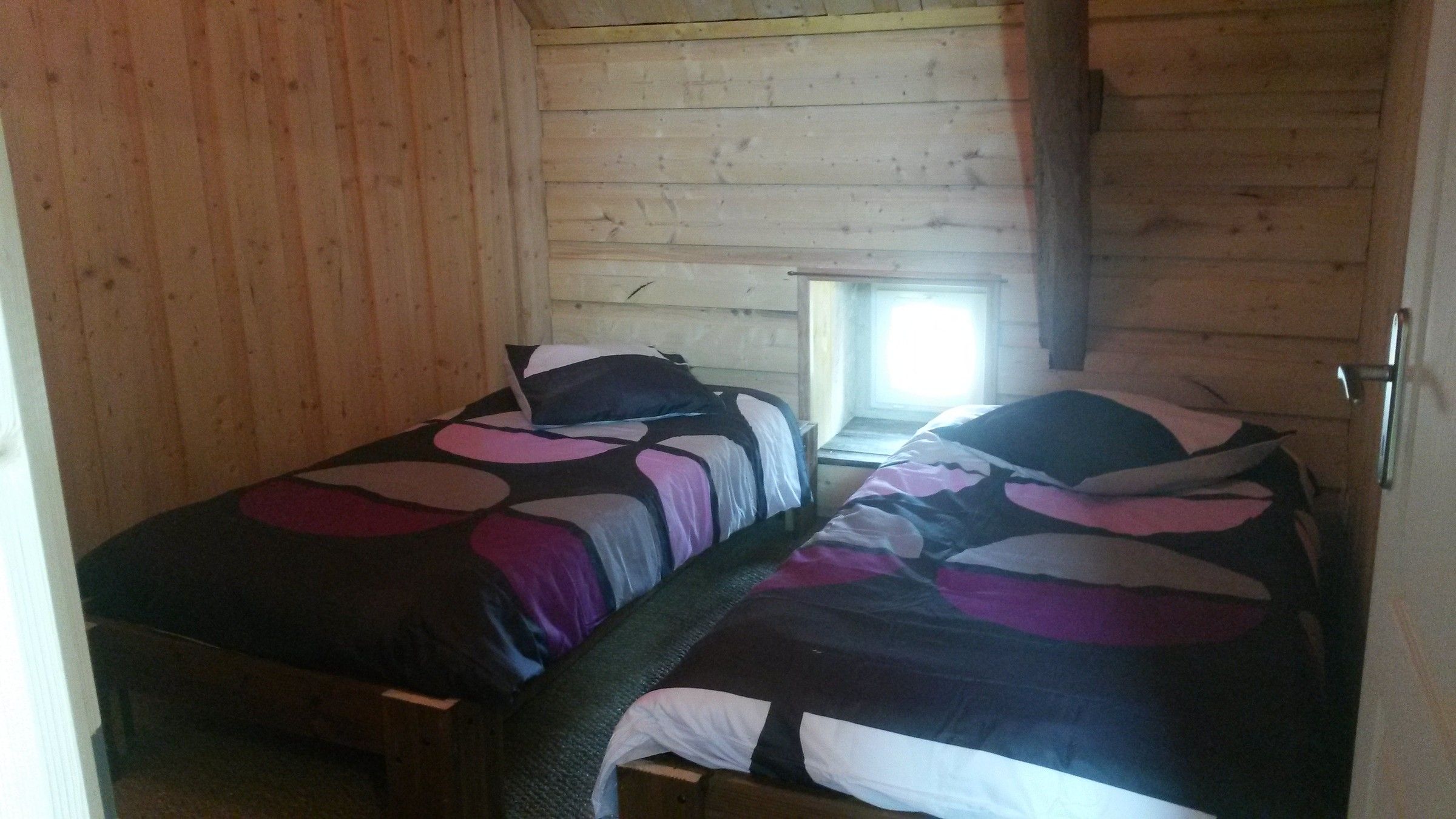 Une chambre de la Sellerie avec deux lits, murs en bois