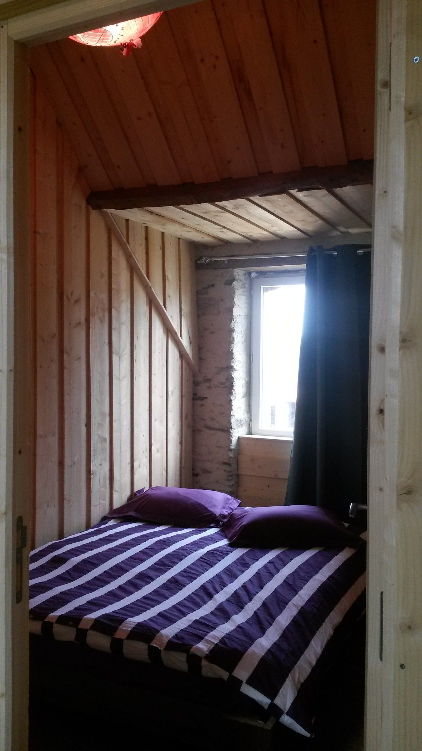 Une chambre de la Sellerie avec un lit double, murs en bois