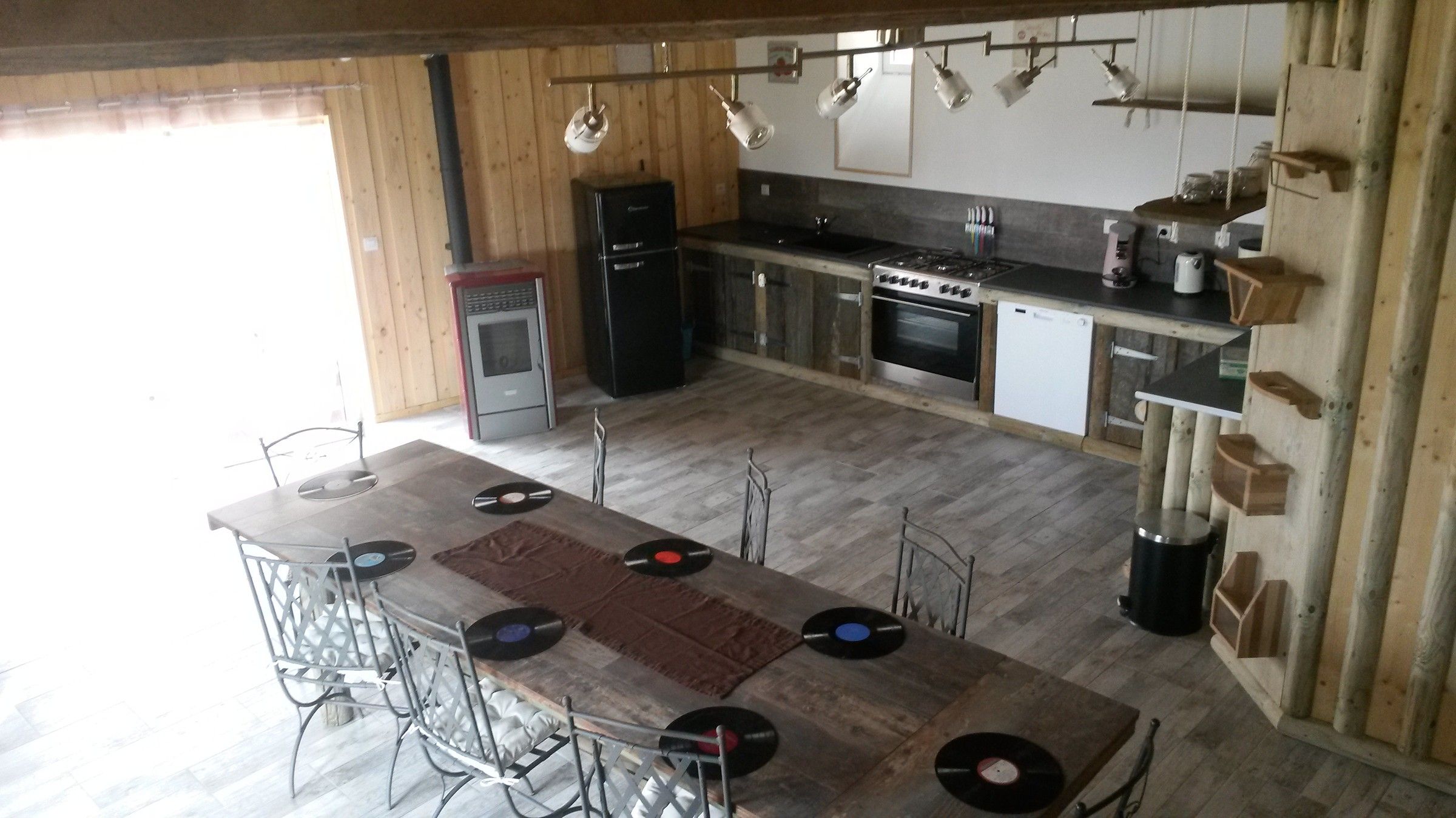 La cuisine de la Sellerie et sa grande table en bois décorée de vinyles
