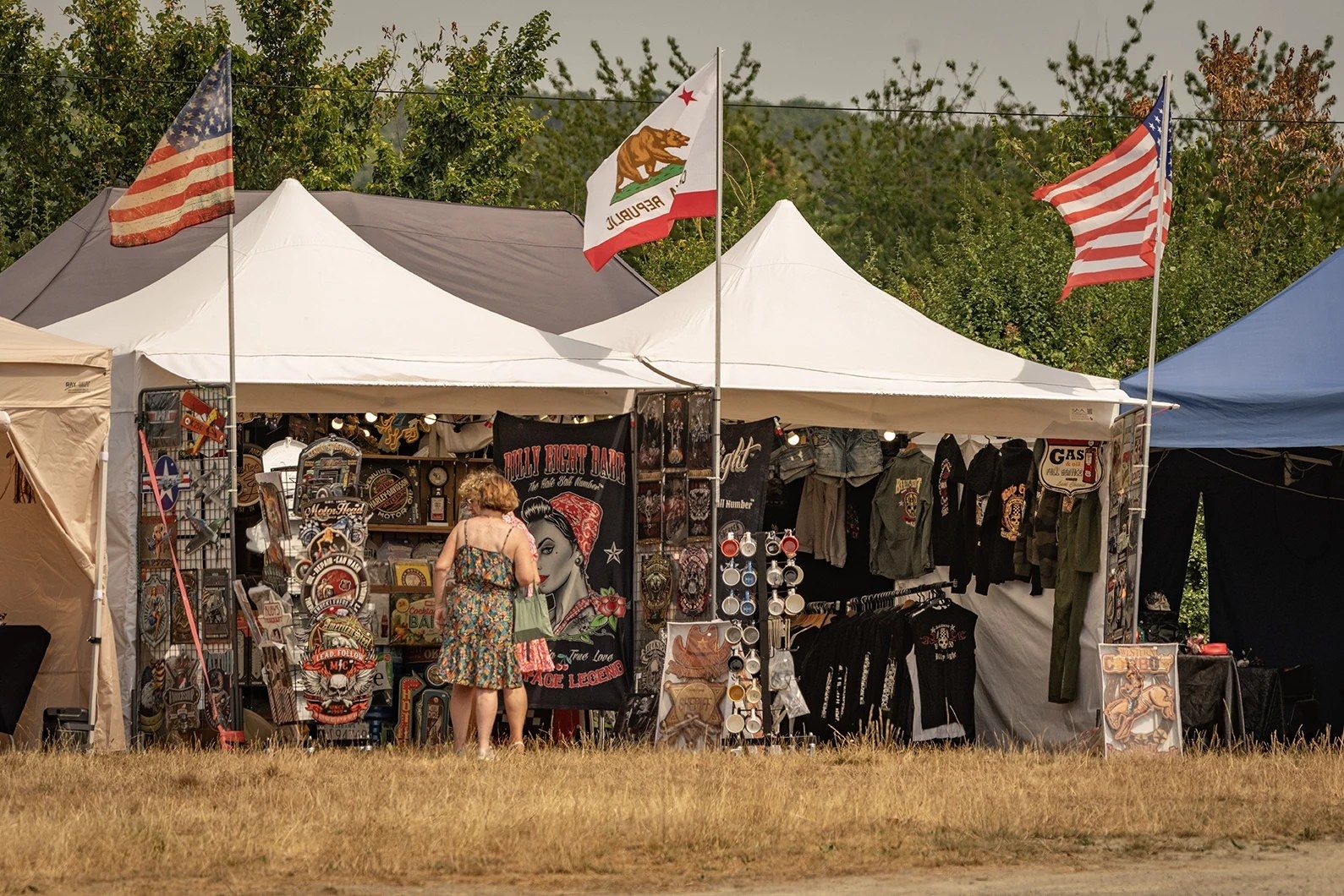 Stand de vêtements western sous une tente, drapeaux américain et californien