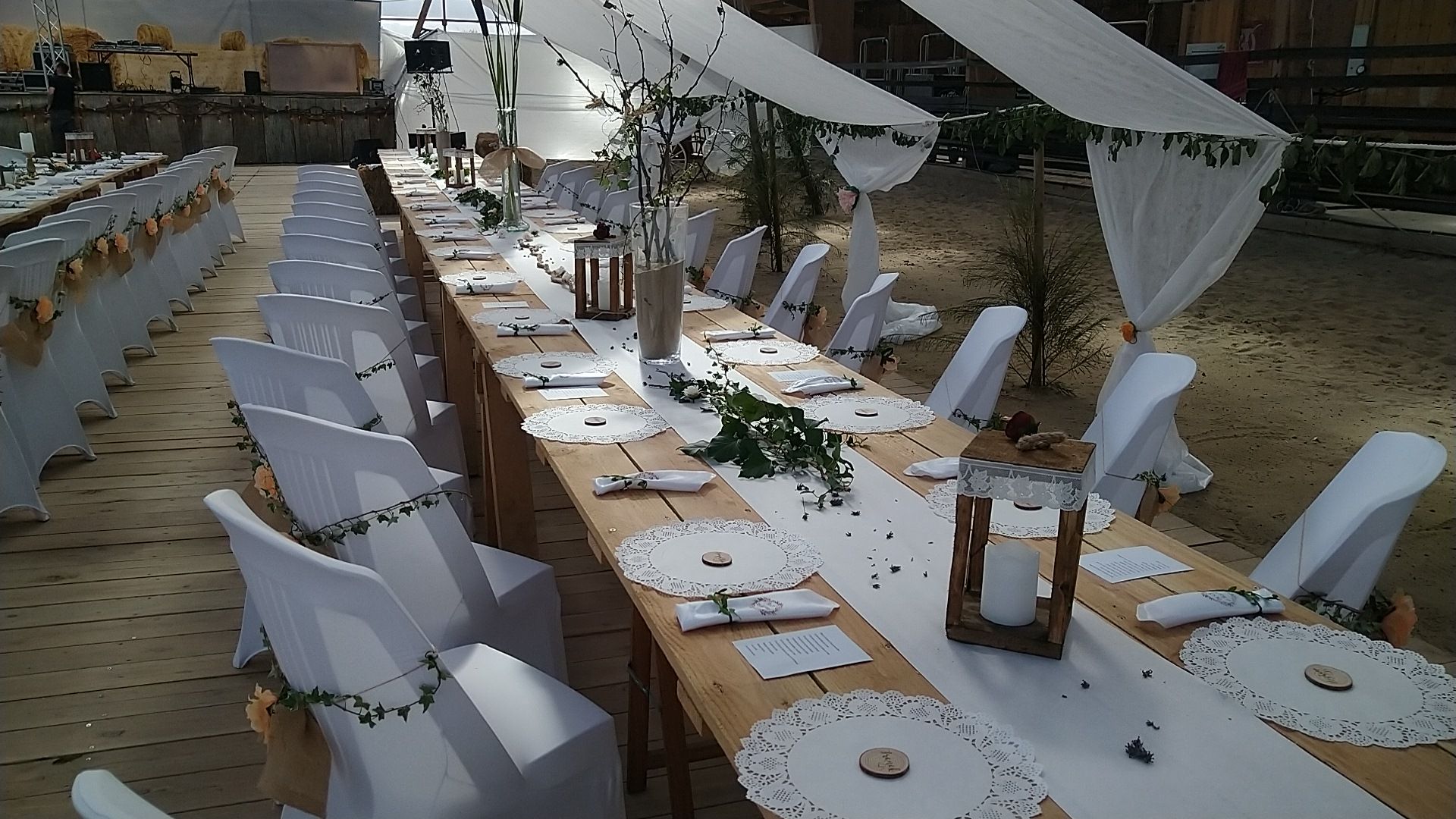 Tables dressées avec lanternes et chaises blanches dans le manège