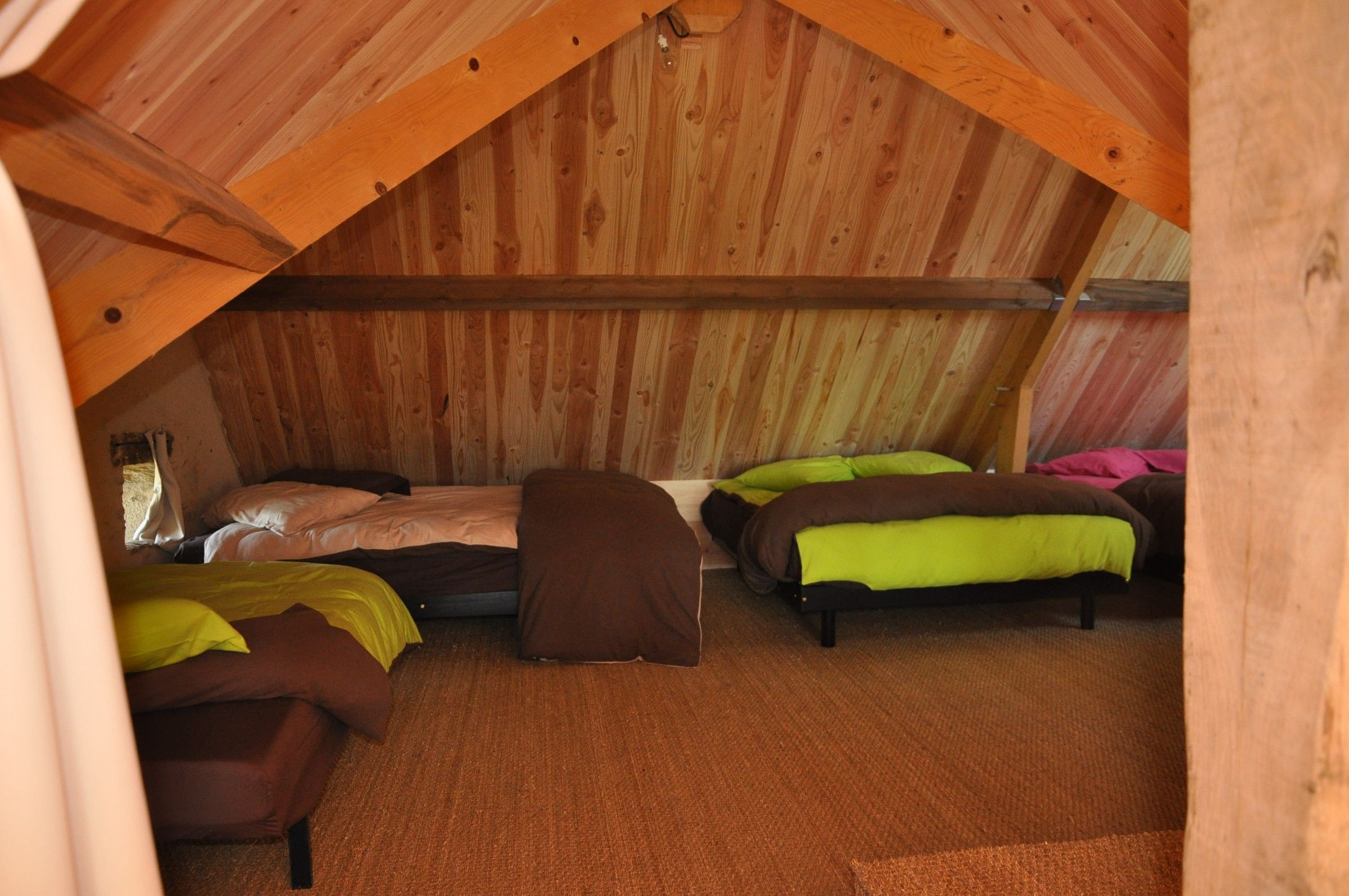 Une chambre sous les combles de la Thom’House, charpente en bois