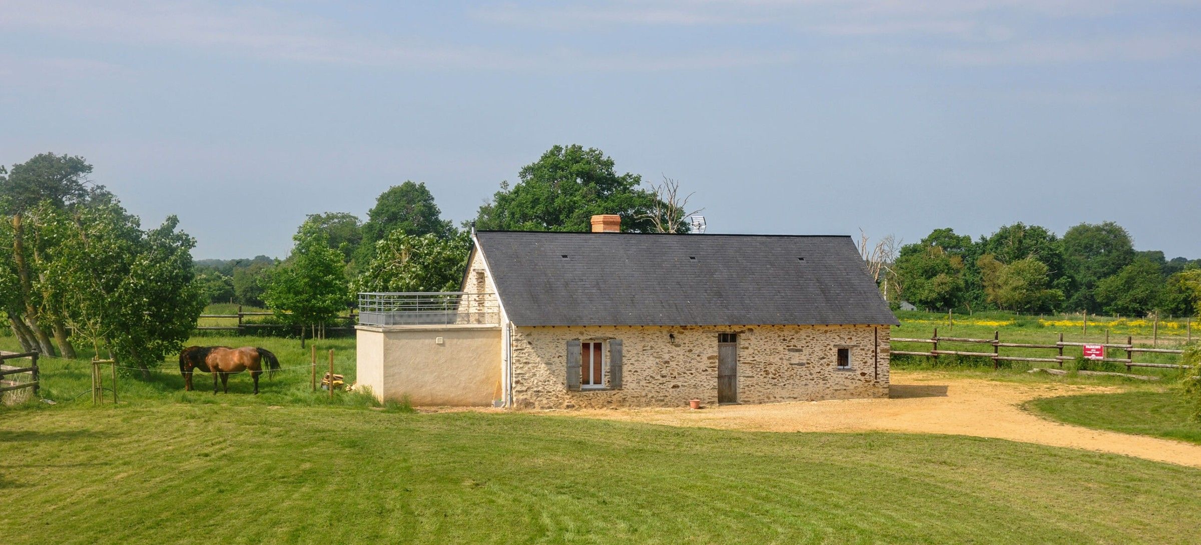 The Thom’House among the fields, with horses grazing