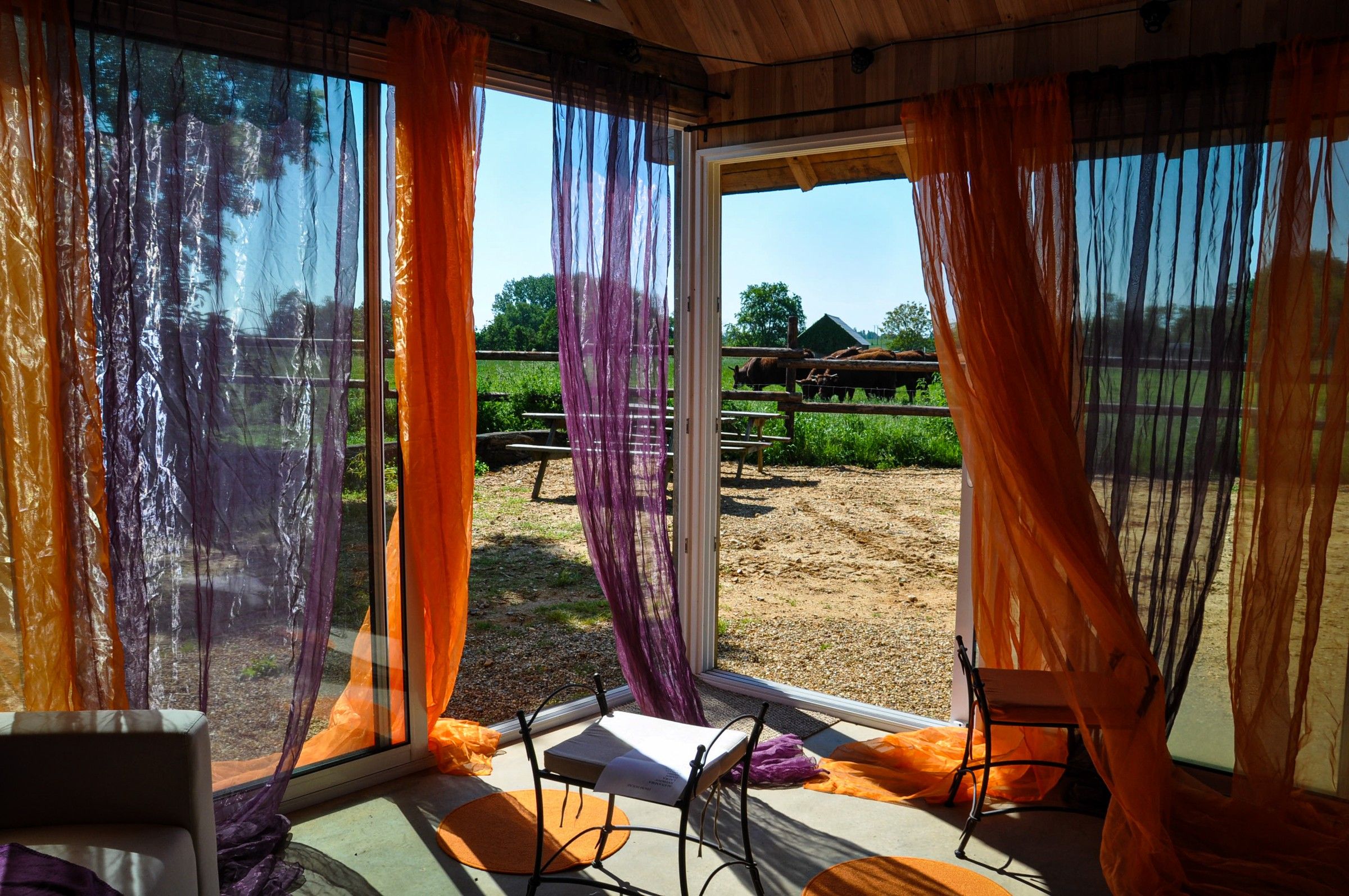 Le petit salon vitré de la Thom’House, voilages orange et violets, vue sur le pré