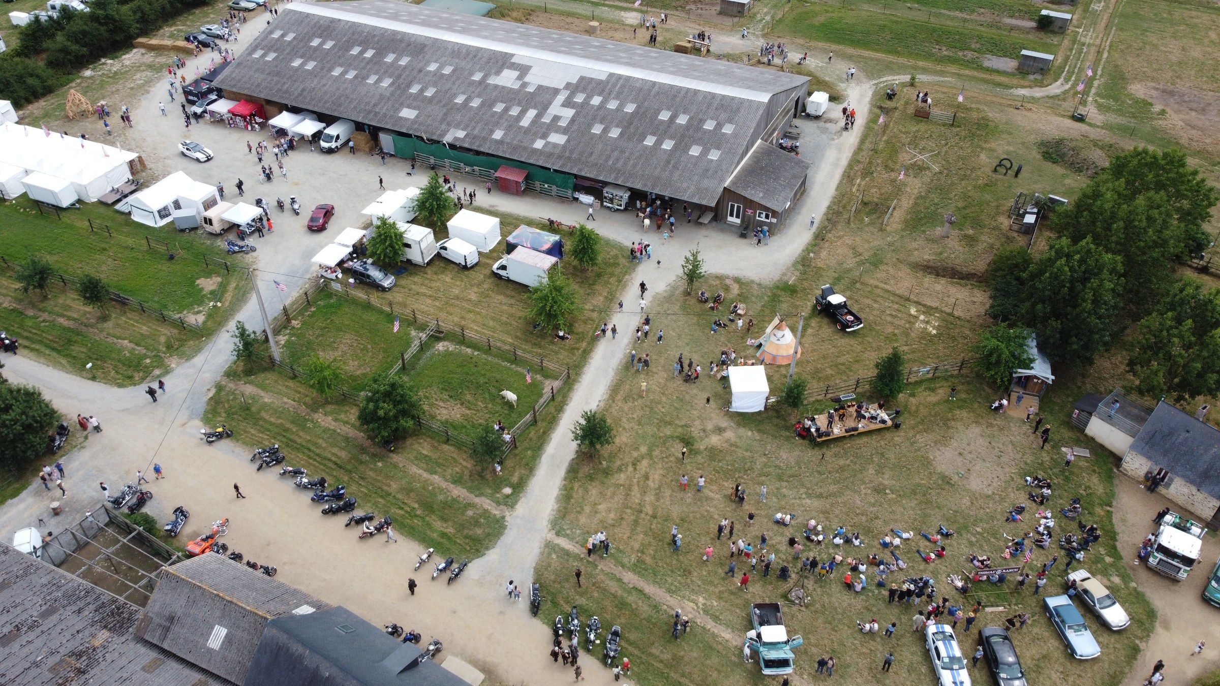 Vue aérienne du festival : le manège couvert, les tentes des exposants et les parkings