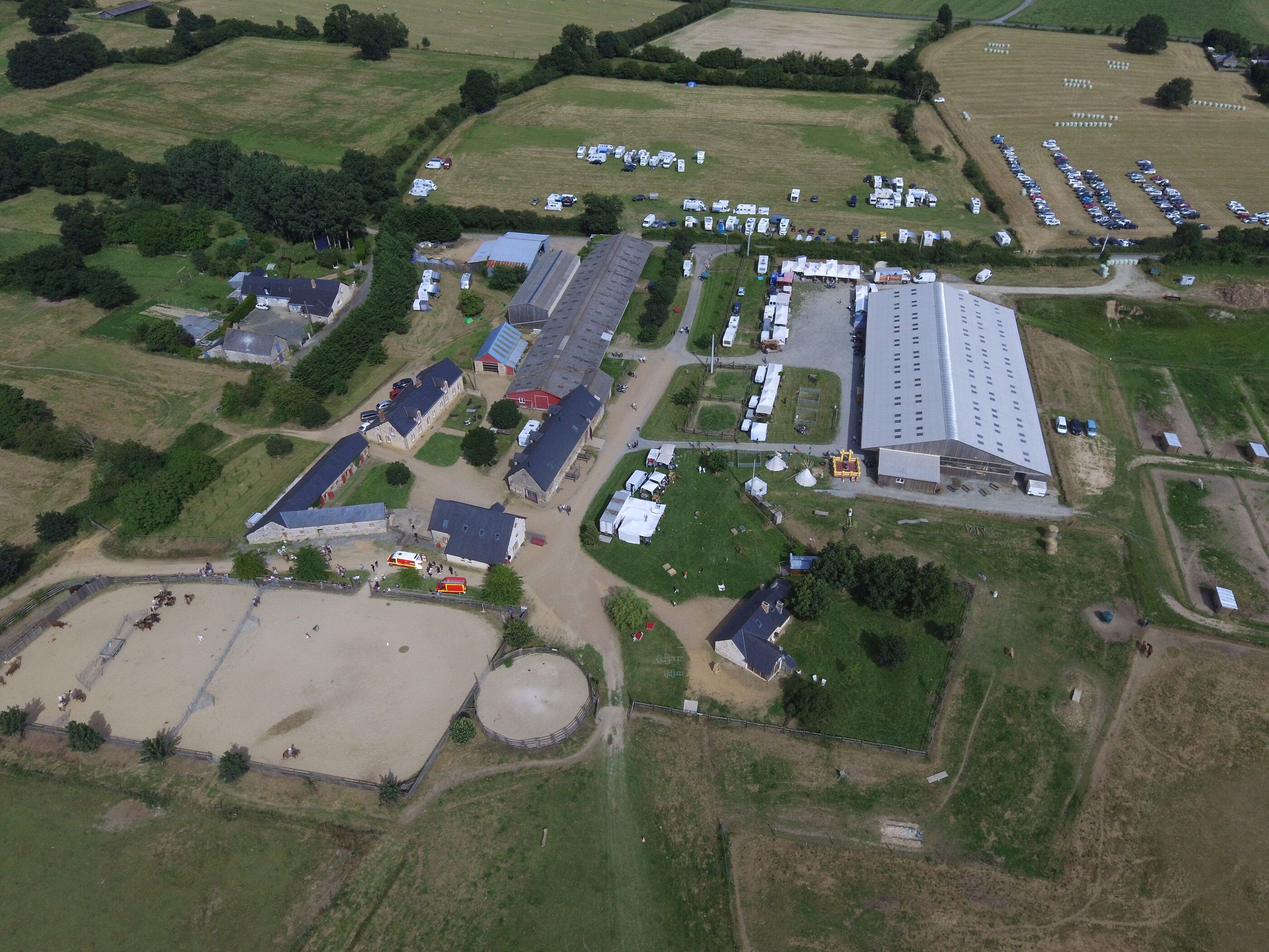 Aerial view of the ranch: indoor arena, stone buildings, outdoor arena, round pen and fields